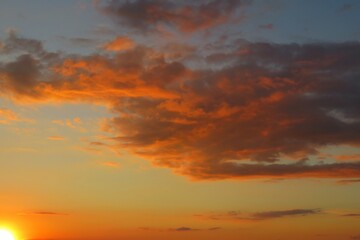 Fototapeta premium Beautiful fiery orange clouds in the sky at sunset, natural cloudscape
