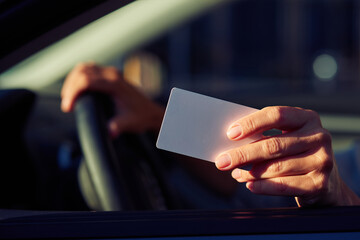 Close up shot of a female hand holding blank plastic card, woman sitting in car and showing driver license identification