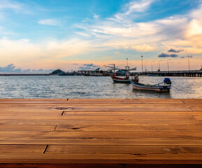 Obraz na płótnie Canvas Beautiful plank wooden table, desk or floor. Blurred background of sunset at sea and local fishing boat. Colourful light on sky. Empty space for product and design or text.