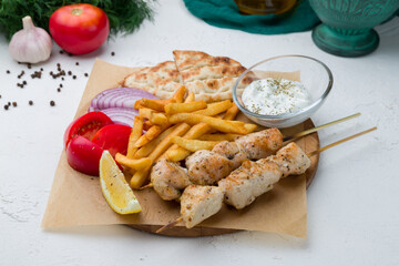 souvlaki with chicken on white concrete table