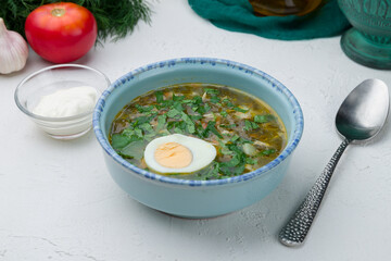 Sorrel soup with egg on white concrete table
