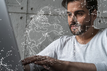A serious caucasian manager in casual wears, using laptop to develop a new worldwide supply chain. Double exposure. globe and map hologram.