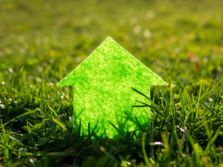 Paper cut house on fresh green grass in the sun. Eco house, investment, construction concept.