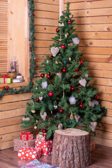 A beautifully decorated corner of a wooden house with Christmas decorated tree and gifts