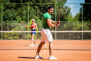 Young athletic couple playing tennis on the court.