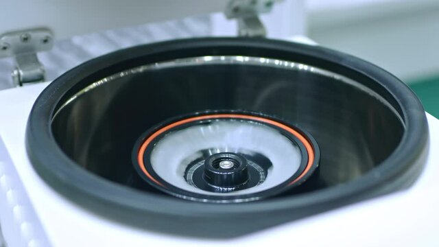 Close up shot of blood samples spinning in centrifuge during fractionation process. Lab worker turning it off, opening lid and taking off test tubes for analyzing.