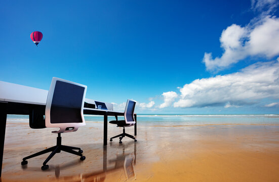 Office Table With Chairs On The Beach Concept Of Remote Work Over Hot Air Balloons