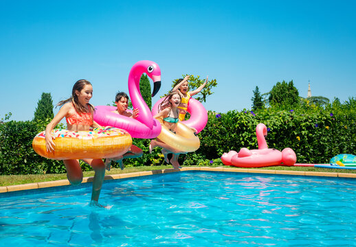 Many of children with inflatable toys donut run and dive in the water pool smiling happily spending vacations