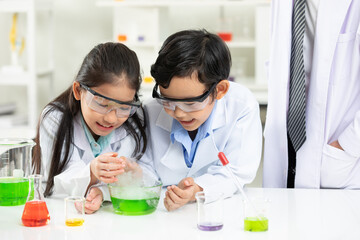 child students doing or testing a chemical experiment with science teacher by them side in laboratory classroom