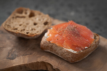 rye ciabatta sandwich with smoked salmon and cream cheese on olive board