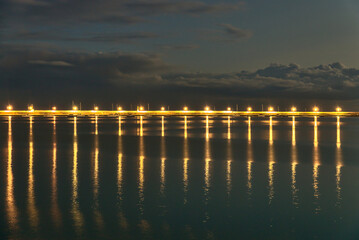 Harbor's lanterns lighting in the evening. Reflection of light in the water. East pier of Dun Laoghaire harbor during the blue hour. Evening shot of famous harbor in Dublin, Ireland