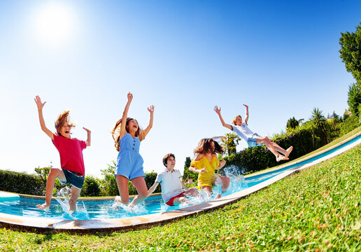 Happy Laughing Group Of Kids Fall And Splash Into The Pool Water Low Angle View Over Blue Sky