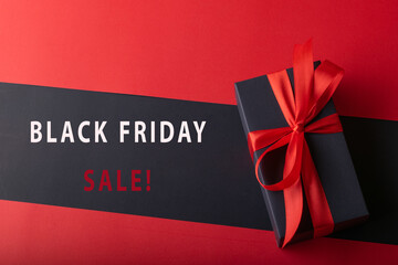 Top view of black boxes with red ribbon on black background and red background. Black Friday and Boxing Day.