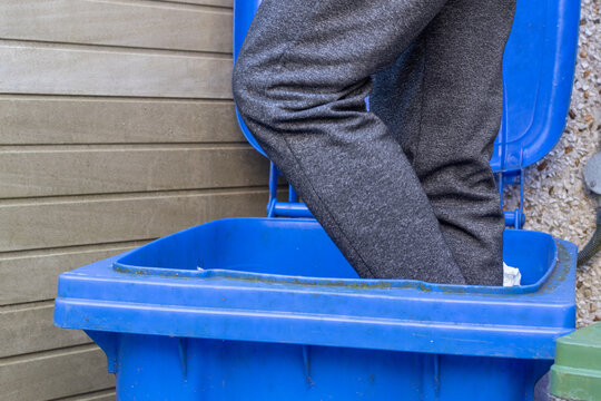 recycling bin beeng compacted by male to reduce cost of recycling