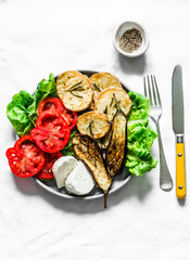 Vegetarian lunch, snack, tapas - rosemary roasted potatoes, grilled eggplant, tomatoes, green salad and greek cheese on a light background, top view