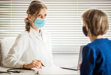 Fototapeta premium female doctor consulting a patient wearing medical mask