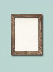 Old rustic wooden picture frame hanging on a light blue wall