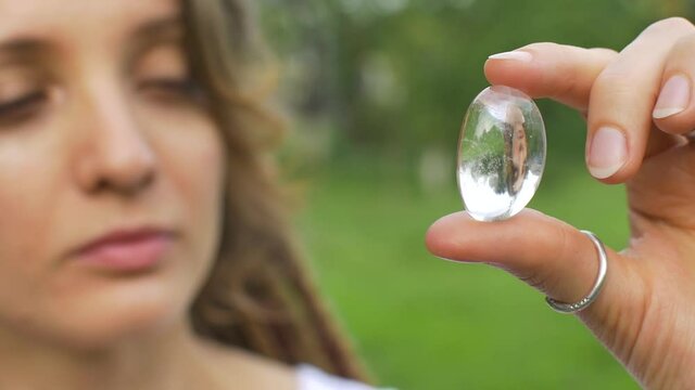 Outdoors portrait of a girl with dreadlocks hairstyle holding in hand little natural stone rock crystal, rhinestone
