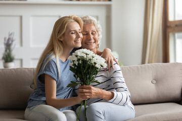 Happy birthday, granny. Happy affectionate grown up female daughter or grandchild cuddling tender...