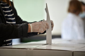 Unrecognizable person casting a vote into the ballot box during corona virus pandemic