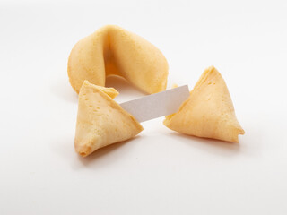 Two fortune cookies with one opened and a small blank piece of pager visible in front of white background