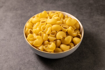 Italian pasta in a bowl, pipe rigate. Concrete background