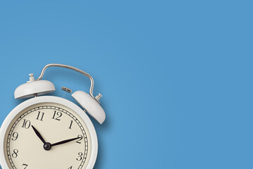 White vintage alarm clock on a blue background. Urgency, deadline and running out of time concept