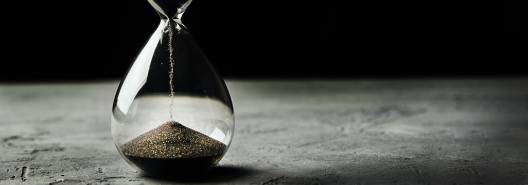 Hourglass on a dark background, long banner. Urgency and running out of time concept