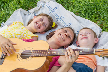 mom with her two children play guitar at the park