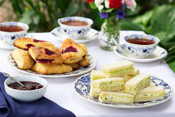 Afternoon tea in the garden with scones, strawberry jam, finger sandwiches with cucumber and egg salad.