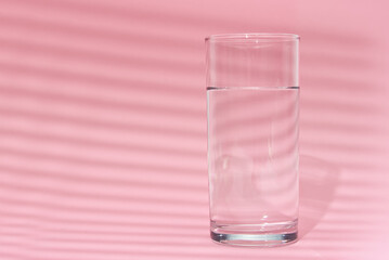 Glass of water on a pink background