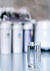 Household filtration system. Water treatment concept. Use of water filters at home. Glass of clean water and filters on a blurred background.