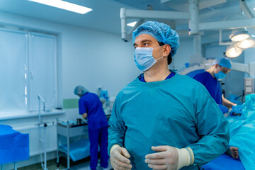 Portrait of a doctor or medical specialist. Horizontal portrait. Man in scrubs. Operating room background with blue light. Closeup.