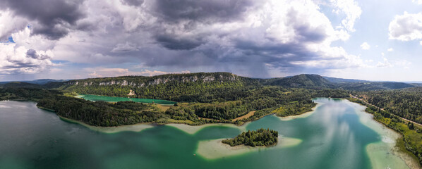 vue panoramique sur  des lacs bleus verts au pied de falaise dans le Jura