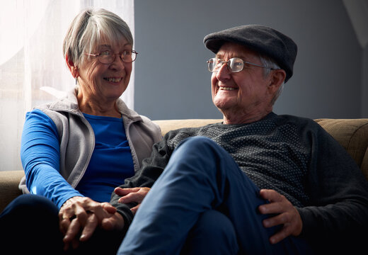 Loving Senior Couple Sitting On Sofa At Home Together