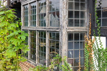Bay window of paintless weathered worn wood with stained glass windows in a house in the United Kingdom