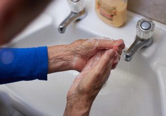 Close Up Of Senior Woman Washing Hands In Washbasin During Health Pandemic
