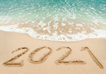 Happy New Year 2021, lettering on the beach with wave and blue sea. Numbers 2021 year on the sea shore, New Years concept.