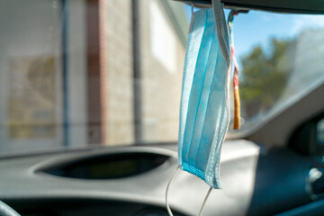 Fototapeta na wymiar Hygienic masks hanging from the rear view mirror inside the car. Daily preparation for the prevention of Coronavirus Covid-19. The concept of Covid-19 protection.