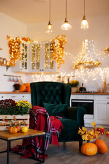 Autumn kitchen studio interior. Red and yellow leaves and flowers in the vase and pumpkin on light background