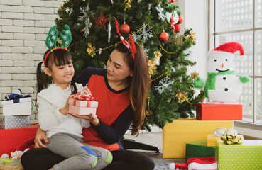 asian mother gives presents to her young daughter in christmas holliday. family together and relationship concept