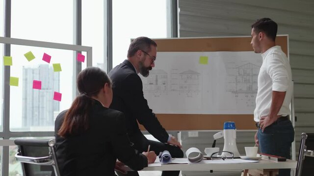 The engineer's team is meeting to discuss work creation in the workroom with documents and work equipment. With a city scene in the background