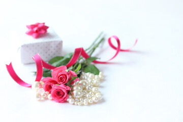 Obraz na płótnie Canvas ホットピンクのバラの花束とパールと贈り物