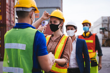 Worker scanning fever temperature with digital thermometer to construction site staff wearing...