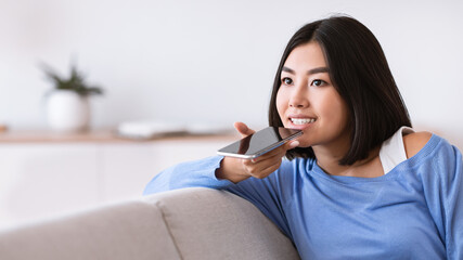 Young woman using voice assistant on smartphone
