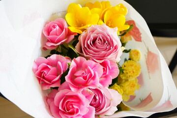 ピンク色のばらと黄色いフリージアの花束