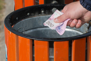 National currency inflation. A man throws a banknote into a trash can.