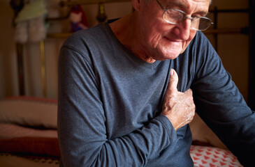 Senior Man With Health Issues At Home Clutching Chest In Pain