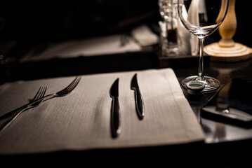 Fototapeta na wymiar still life with knives and forks on a napkin on a dark background