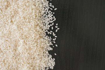 Top view of rice on black wooden background.